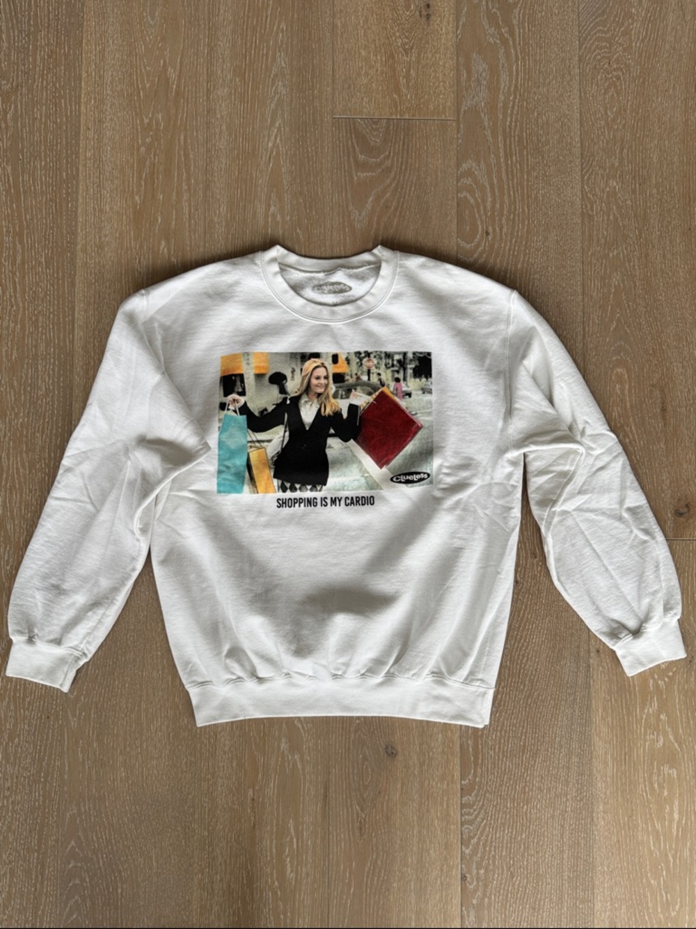 Clueless “Shopping Is My Cardio” Women’s Graphic White Crewneck Sweatshirt.
